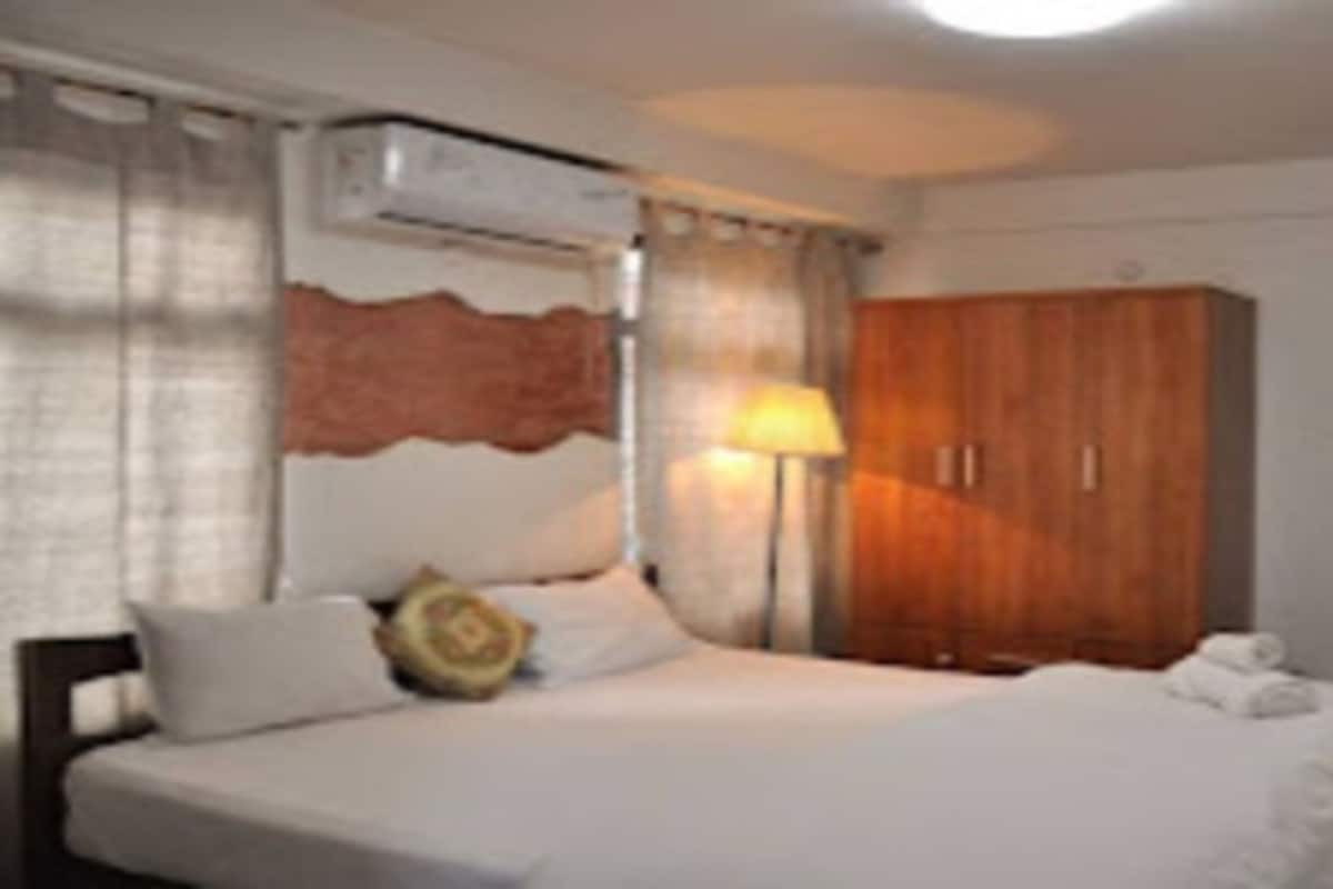 A hotel room with a bed, a wardrobe, and a lamp.