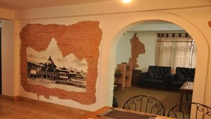 Habitación con un mural de un edificio histórico, un sofá de cuero negro y una mesa de comedor con sillas de metal.