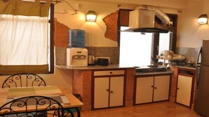 Una cocina funcional con dispensador de agua, estufa y refrigerador.