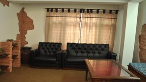 Una sala de estar con dos sofás de cuero negro, una mesa de centro de vidrio y una pared decorativa de ladrillo.