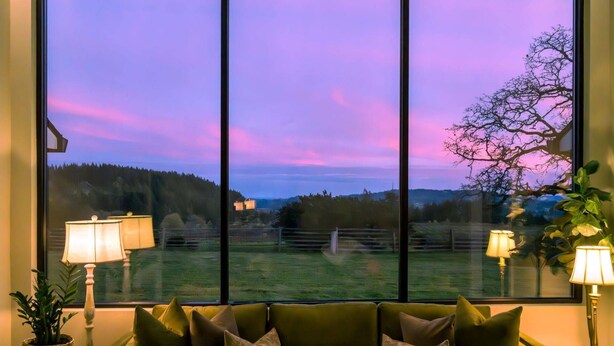 A room with a large window, a sofa, and two lamps. - Picturesque Panoramic Vineyard Views From Home and Hot Tub, Pet Friendly, Private, Fire-Pit, BBQ (Newberg)