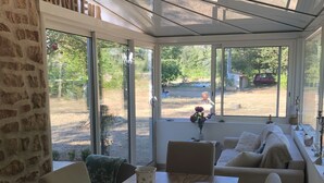 Una habitación acogedora con una mesa de madera, un banco acolchado y un ventanal con vistas al exterior.