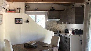 Una cocina acogedora con armarios de madera, una mesa de comedor con sillas y una pequeña isla con un bol.