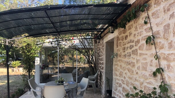 Un patio al aire libre con una mesa, sillas, una parrilla y un muro de piedra.