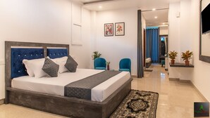 A modern bedroom with a large bed, a blue headboard, and a view into the hallway. - The Green Land Kasauli  (Kasauli)