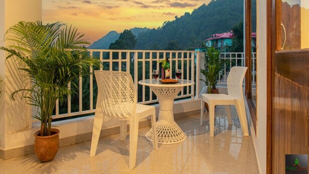 A balcony with white chairs, a table, and potted plants. - The Green Land Kasauli  (Kasauli)