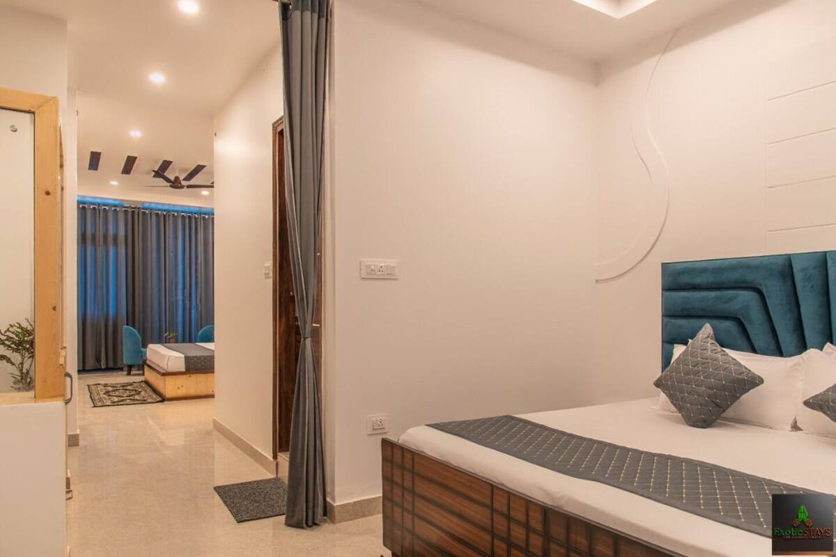 Een moderne slaapkamer met een bed, een hoofdeinde en uitzicht op een andere kamer met een bureau en stoel.