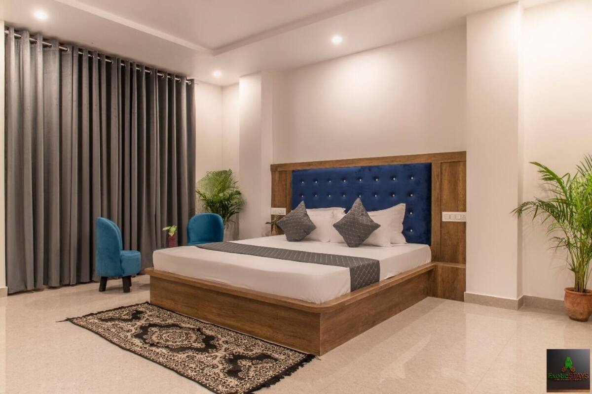 Een moderne slaapkamer met een houten bedframe, een gestuikt hoofdeinde en een kamerkleed met een patroon.