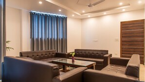 A modern living room with a sofa set, a coffee table, and a large window with curtains. - The Green Land Kasauli  (Kasauli)