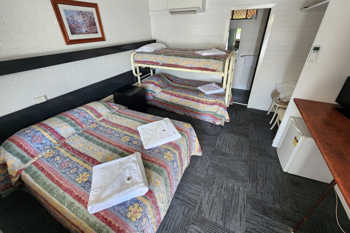 A hotel room with two bunk beds, a desk, a chair, and a small table.
