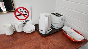 Une petite cuisine équipée d’une machine à café, d’un grille-pain, de tasses, d’assiettes et d’un panier contenant une serviette.