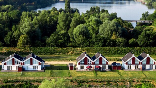 En rad moderna hus med en sjö och en skog i bakgrunden.