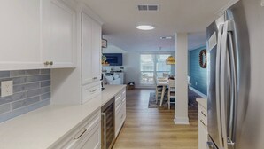 Una cocina moderna con armarios blancos, un refrigerador de acero inoxidable y un comedor con una pared de acento azul.