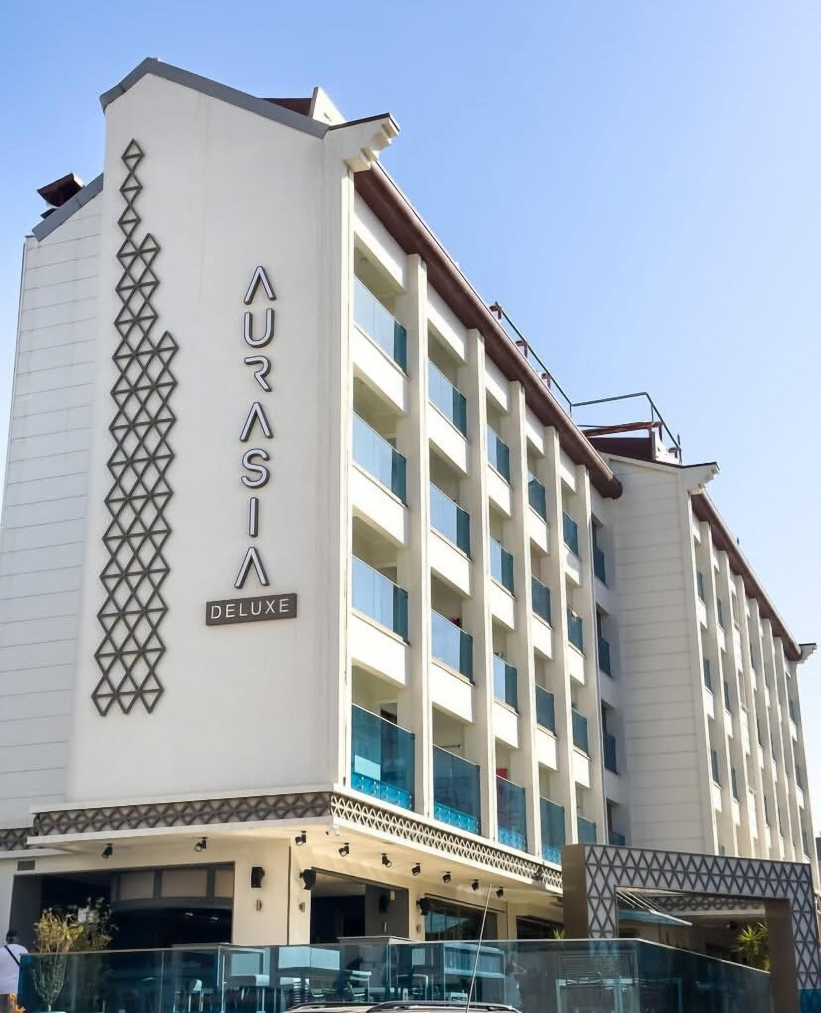 Ein mehrstöckiges Hotel mit einem auffälligen Schild, auf dem "AURASIA DELUXE" steht.
