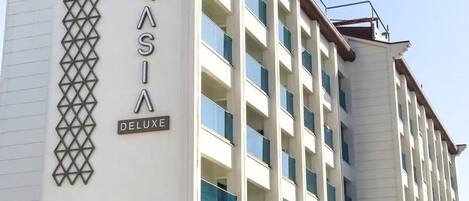Ein mehrstöckiges Hotel mit einem auffälligen Schild, auf dem "AURASIA DELUXE" steht.