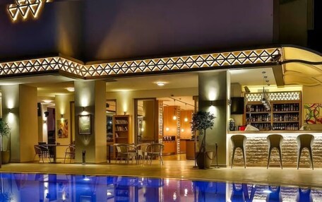 A swimming pool with a geometric light design, a bar area with a patterned ceiling, and a library with bookshelves.