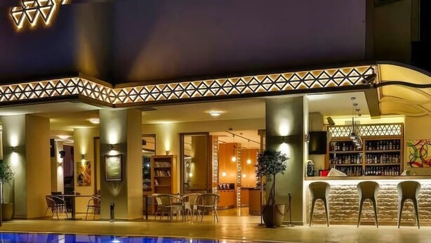 A swimming pool with a geometric light design, a bar area with a patterned ceiling, and a library with bookshelves. - Aurasia Design Hotel (Marmaris)