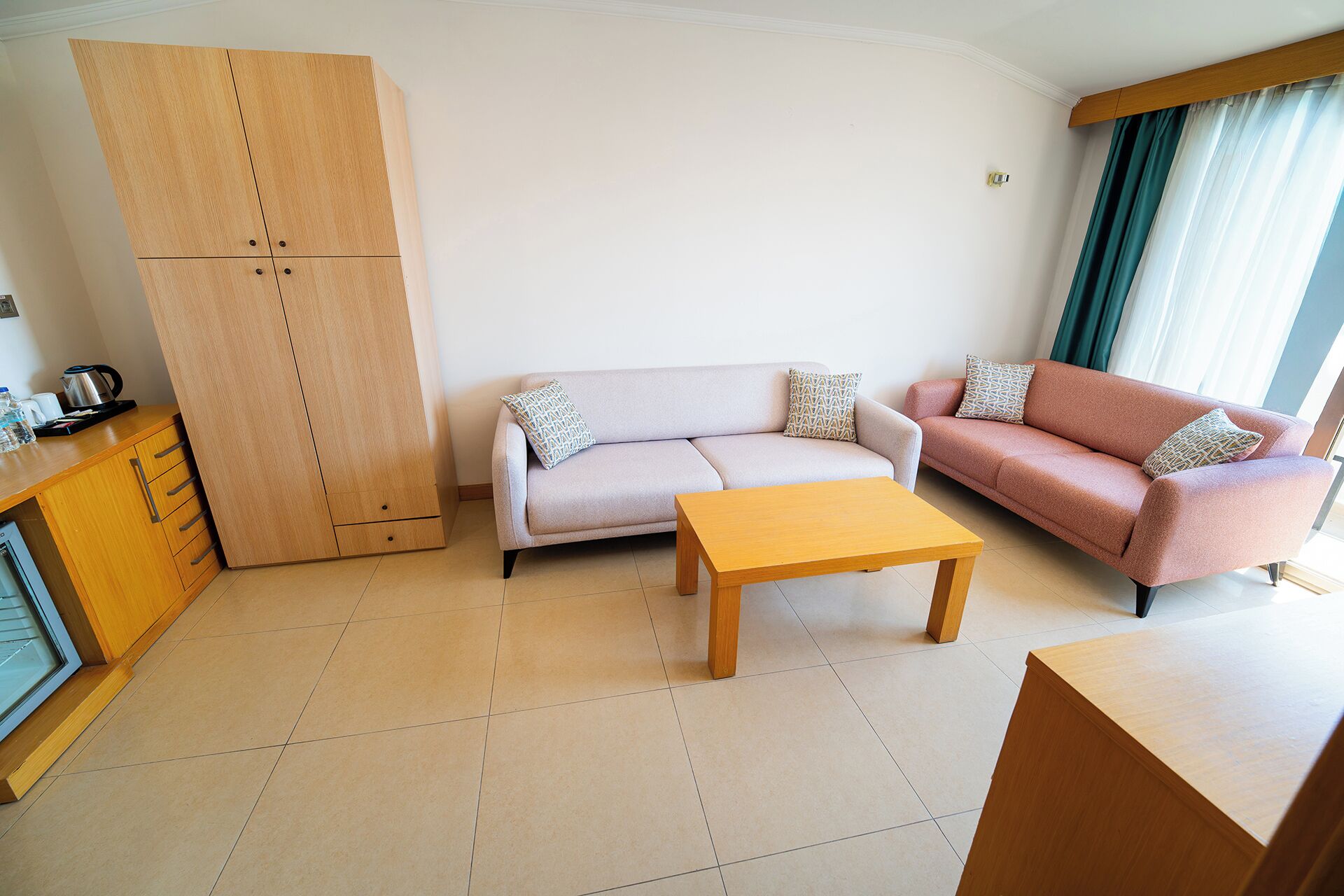 A modern living room with a sofa, a coffee table, a cabinet, and a kitchenette area.