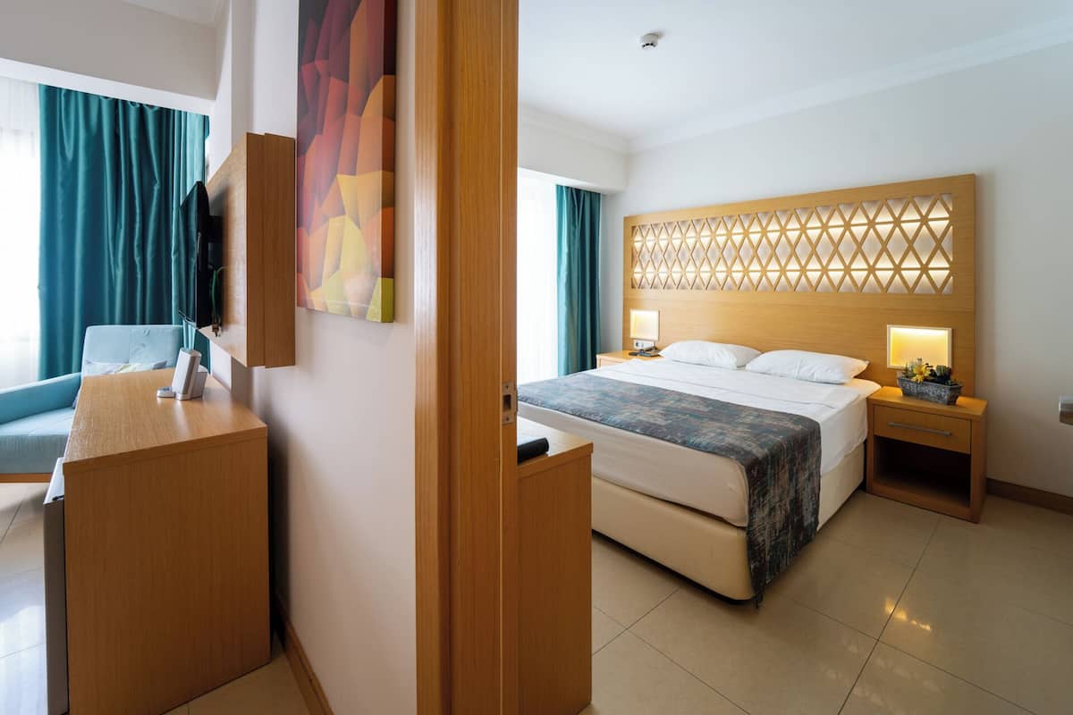 A hotel room with a bed, bedside tables, a desk, and a chair.
