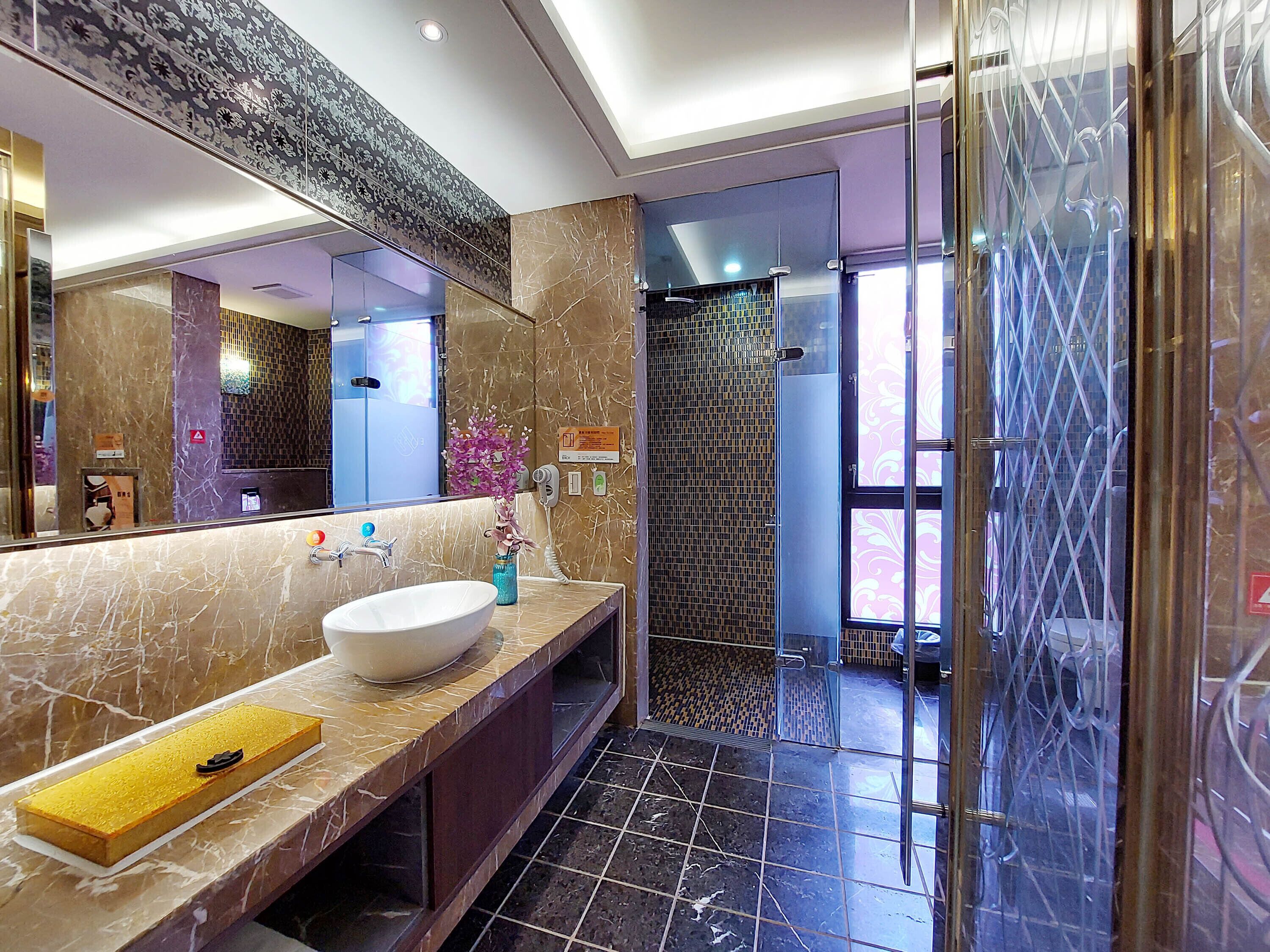 Un baño moderno con un espejo grande, un lavabo blanco y una zona de ducha.