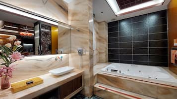 A modern bathroom with a large mirror, a white sink, a vanity, a built-in shower, and a marble floor.