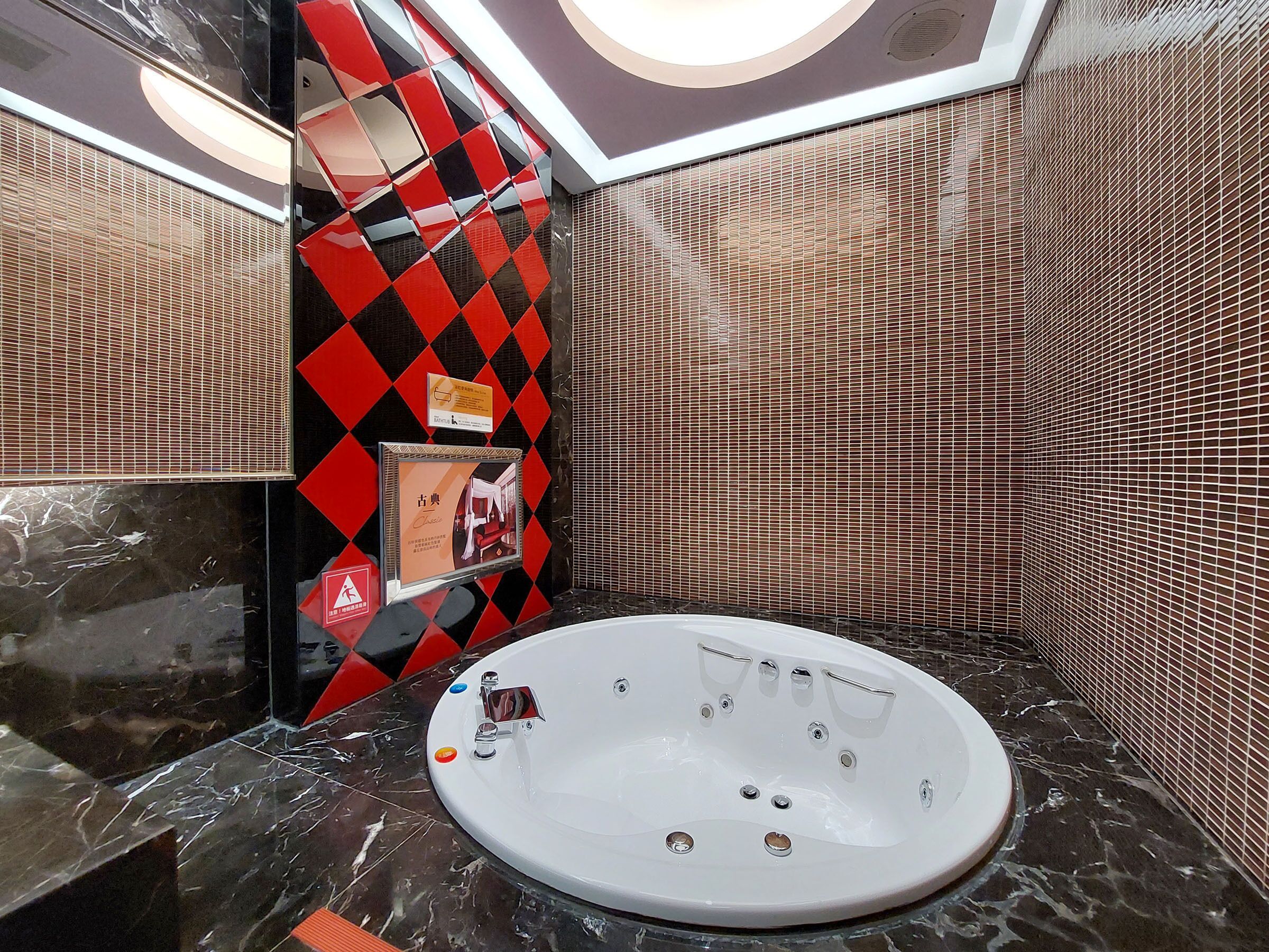 A modern bathroom with a freestanding bathtub, a tiled wall with a diamond pattern, and a framed picture on the wall.