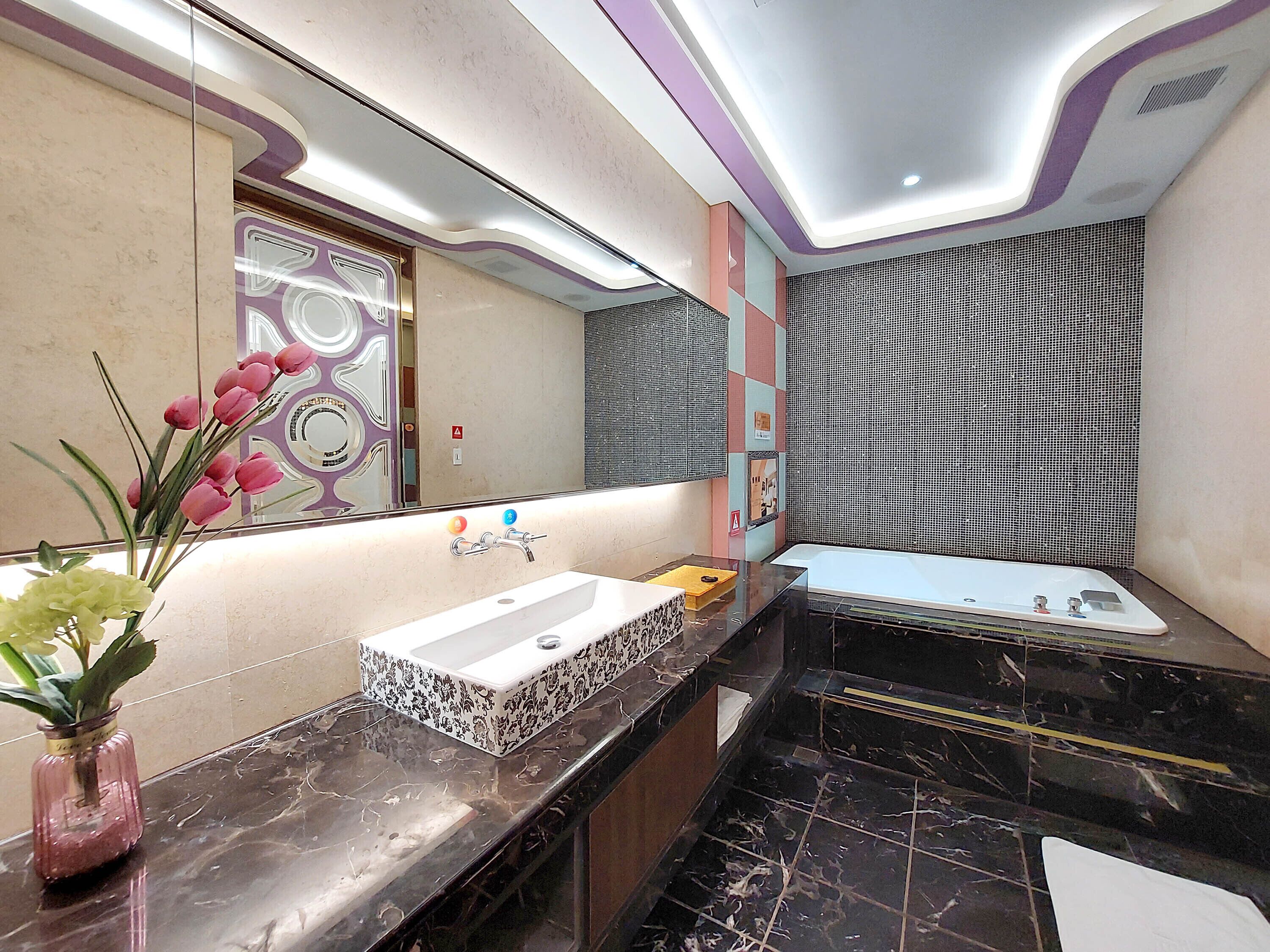 A modern bathroom with two sinks, a mirror, and a decorative wall.