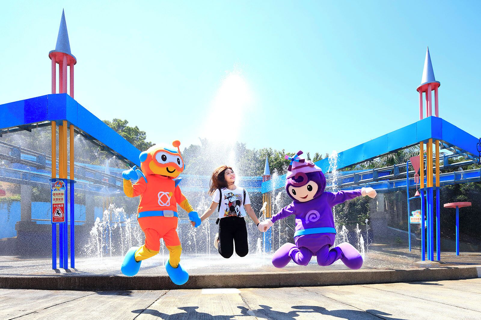 A water fountain area with two mascots and a person.