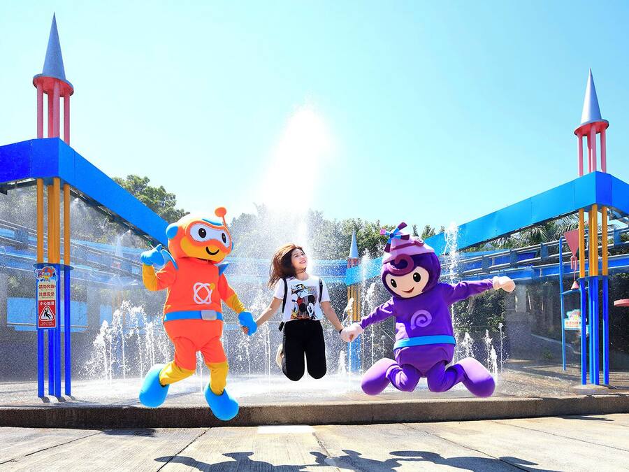 A water fountain area with two mascots and a person.