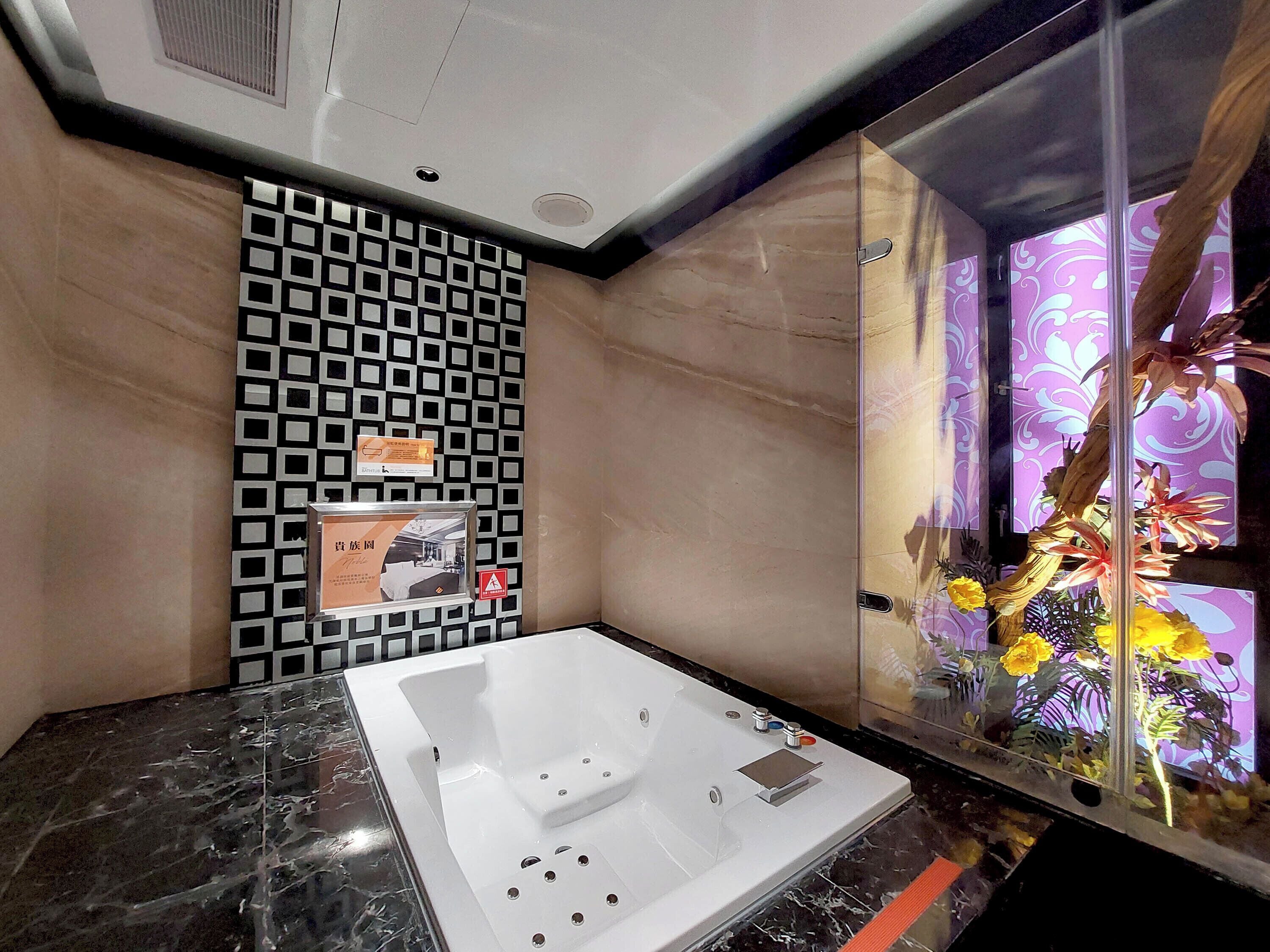 Un baño moderno con una bañera grande, un papel tapiz estampado y una decoración vegetal.