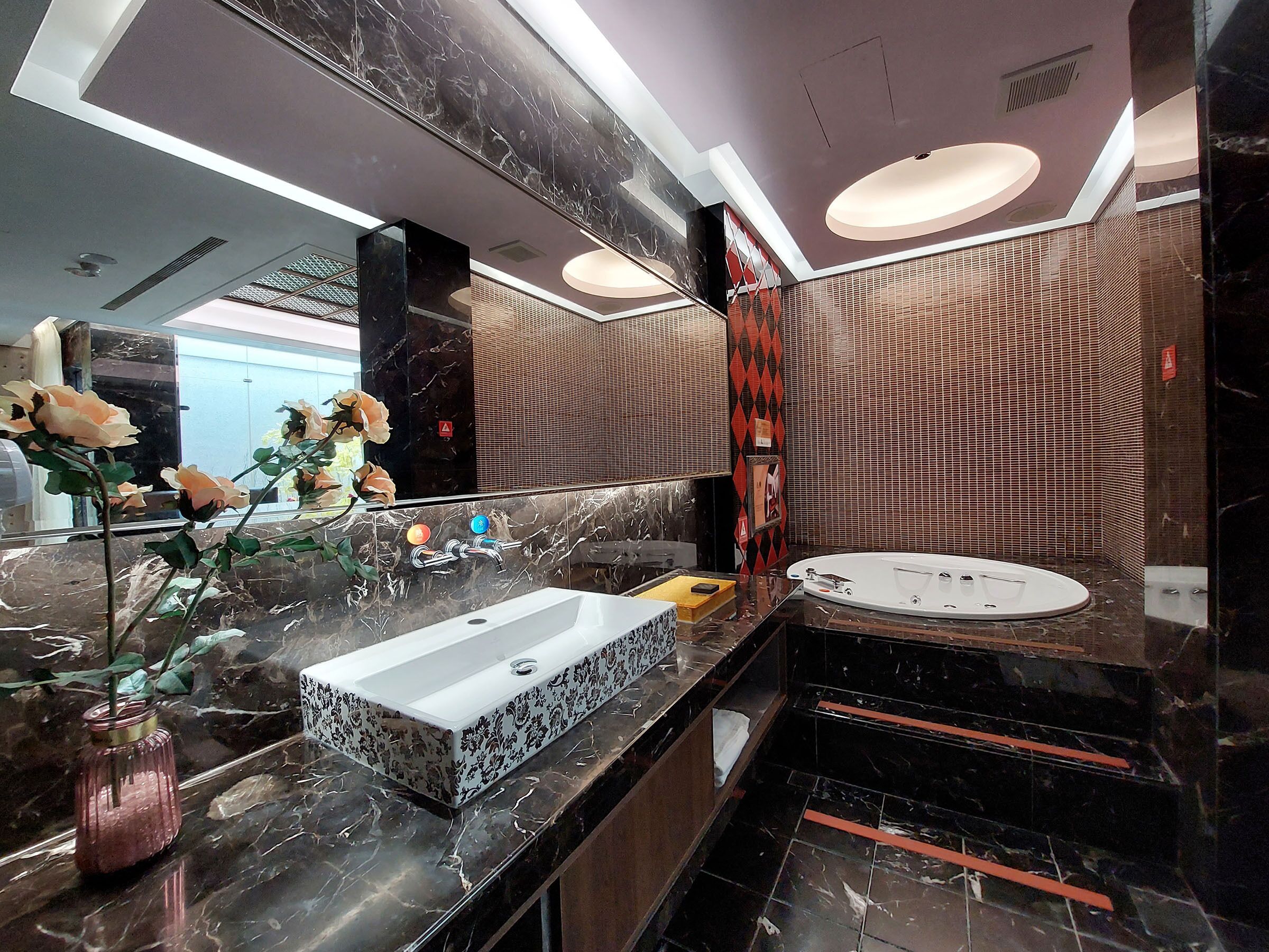 A modern bathroom with a large mirror, two sinks, and a marble countertop.