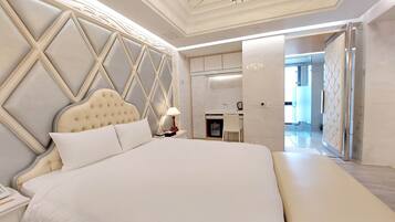 A spacious bedroom with a large bed, a nightstand, a desk, and a chair.