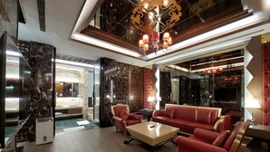 A modern lobby with a red sofa set, a glass coffee table, and a decorative chandelier. - ELYSEES MOTEL (Toufen)