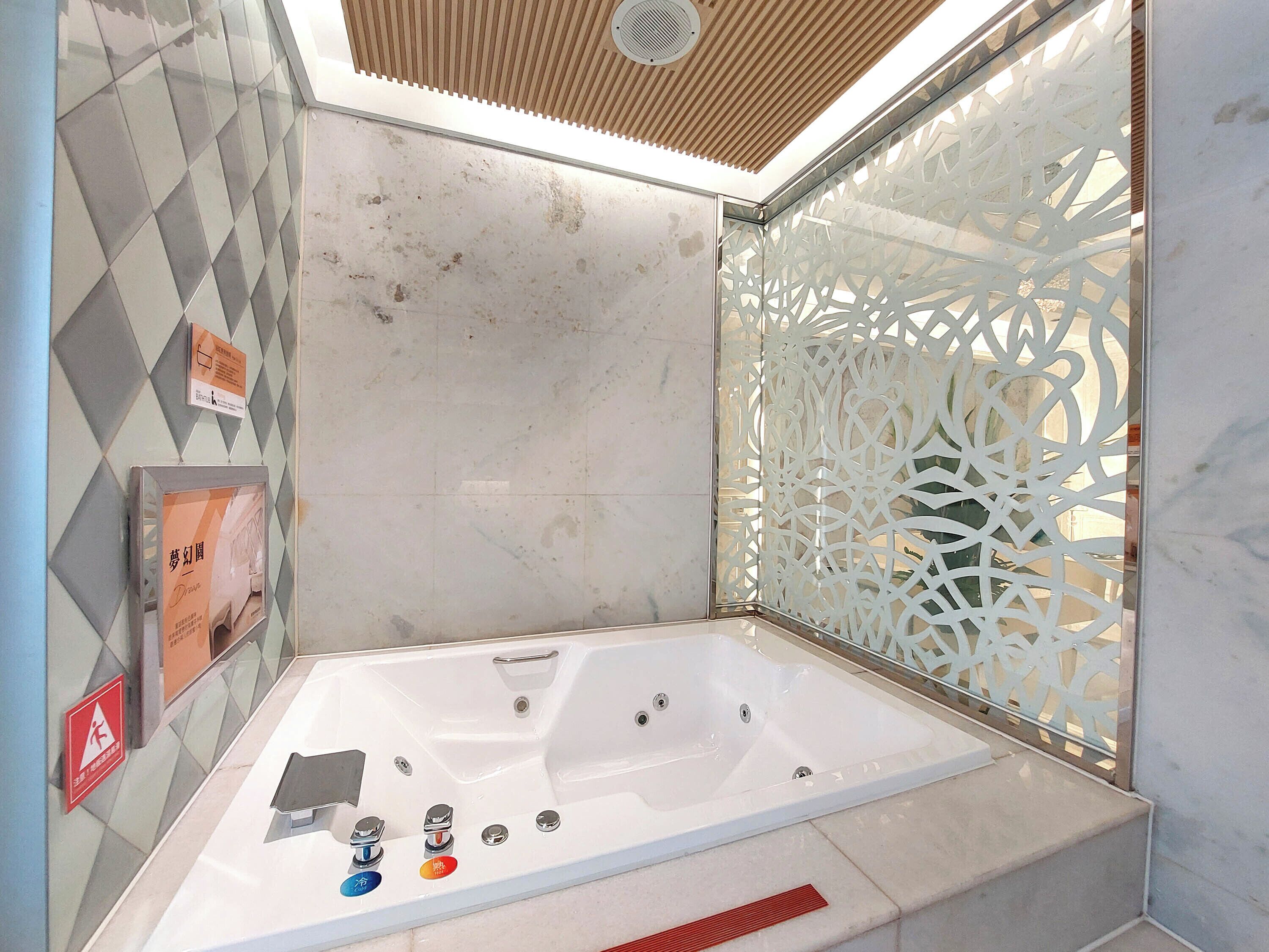 A modern bathroom with a freestanding bathtub, a shower area, and a decorative screen.