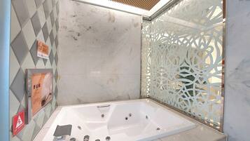 A modern bathroom with a freestanding bathtub, a shower area, and a decorative screen.