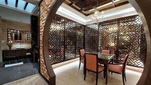 A dining area with a glass table and chairs, surrounded by a decorative wooden partition with geometric patterns. - ELYSEES MOTEL (Toufen)