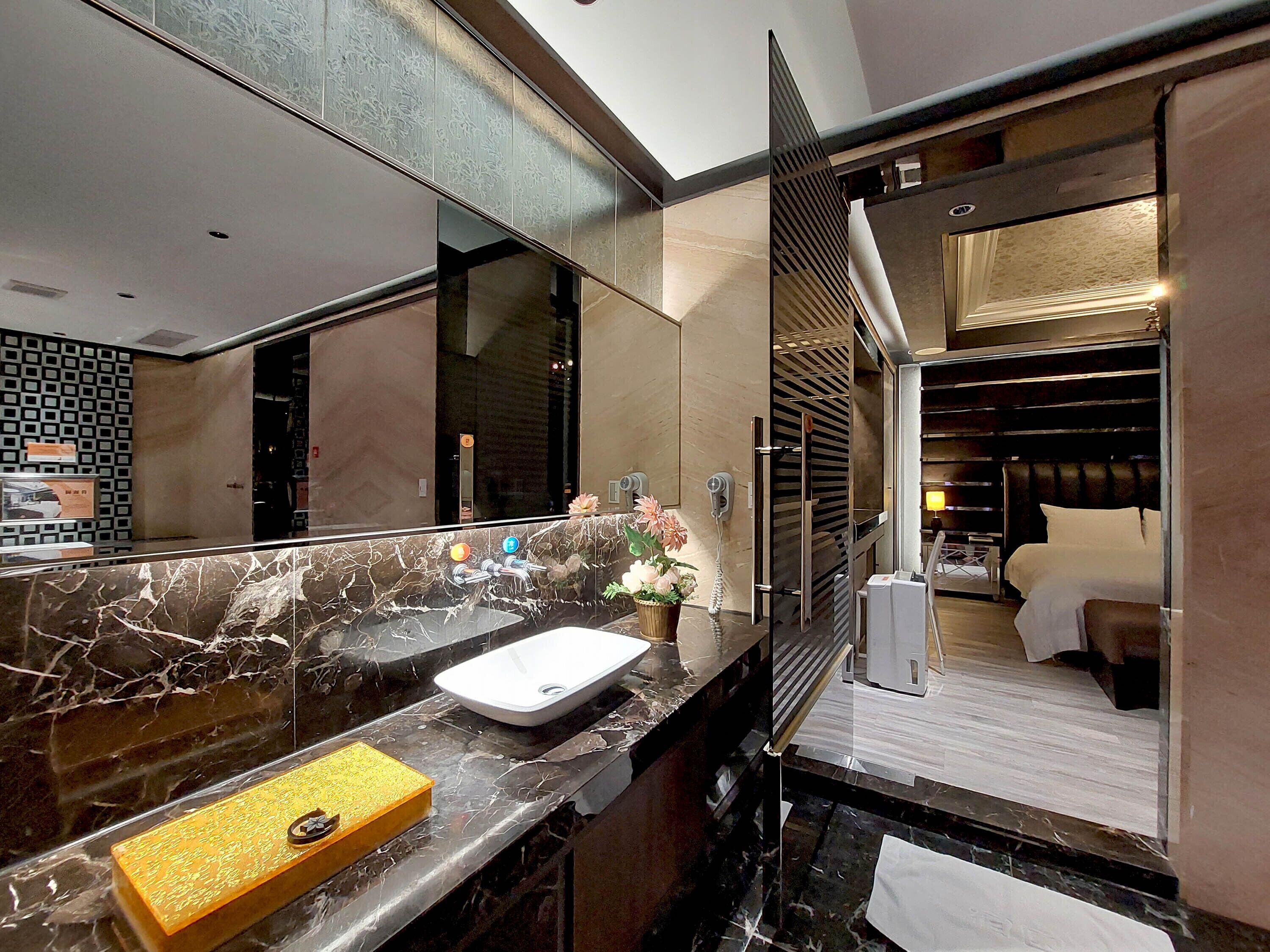 A modern bathroom with a marble countertop, a white sink, and a mirror.