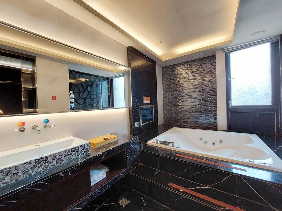 Een moderne badkamer met een grote spiegel, een badkuip en een wastafel met een marmeren blad.