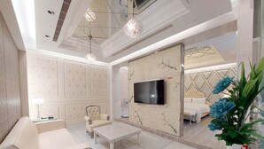 A modern living room with a flat-screen TV, a sofa, a coffee table, and a decorative plant. - ELYSEES MOTEL (Toufen)