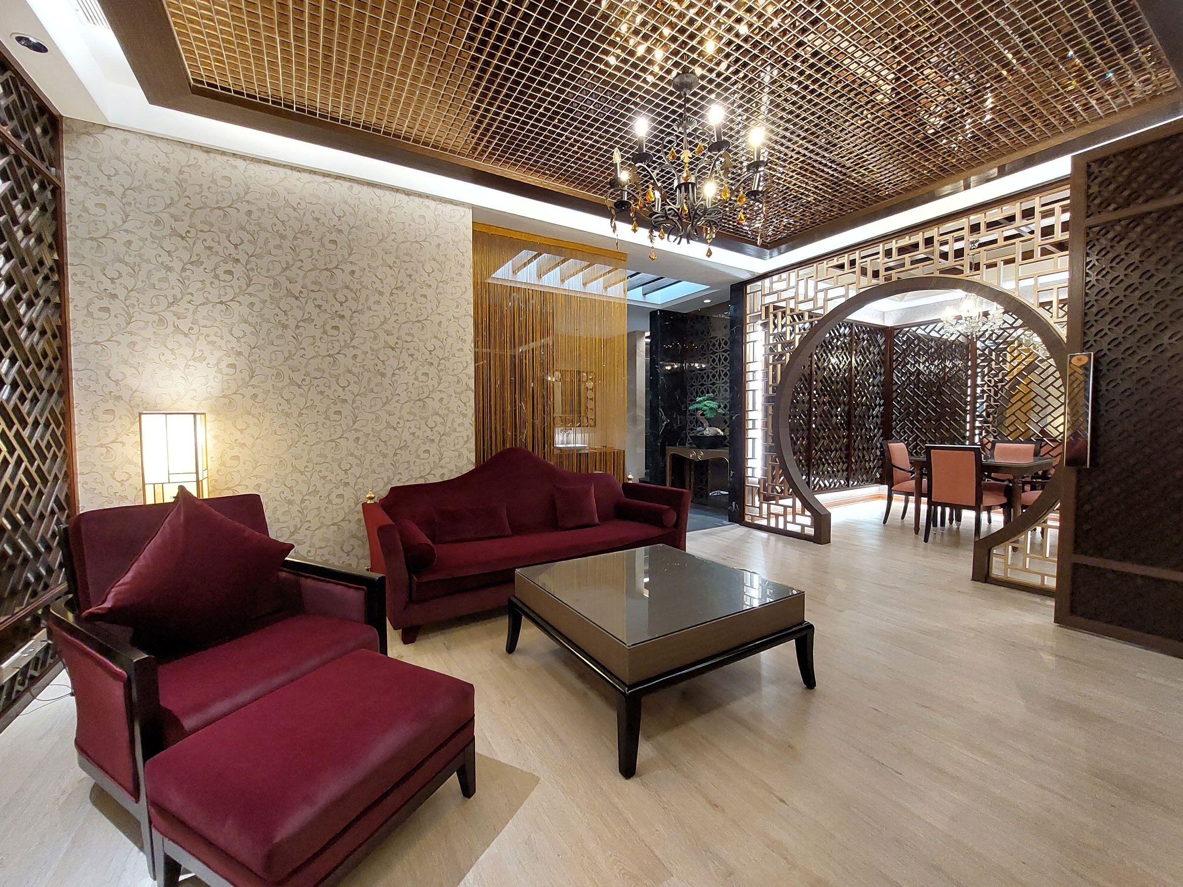 A spacious lobby with a red sofa set, a coffee table, and a dining area with chairs and a table.