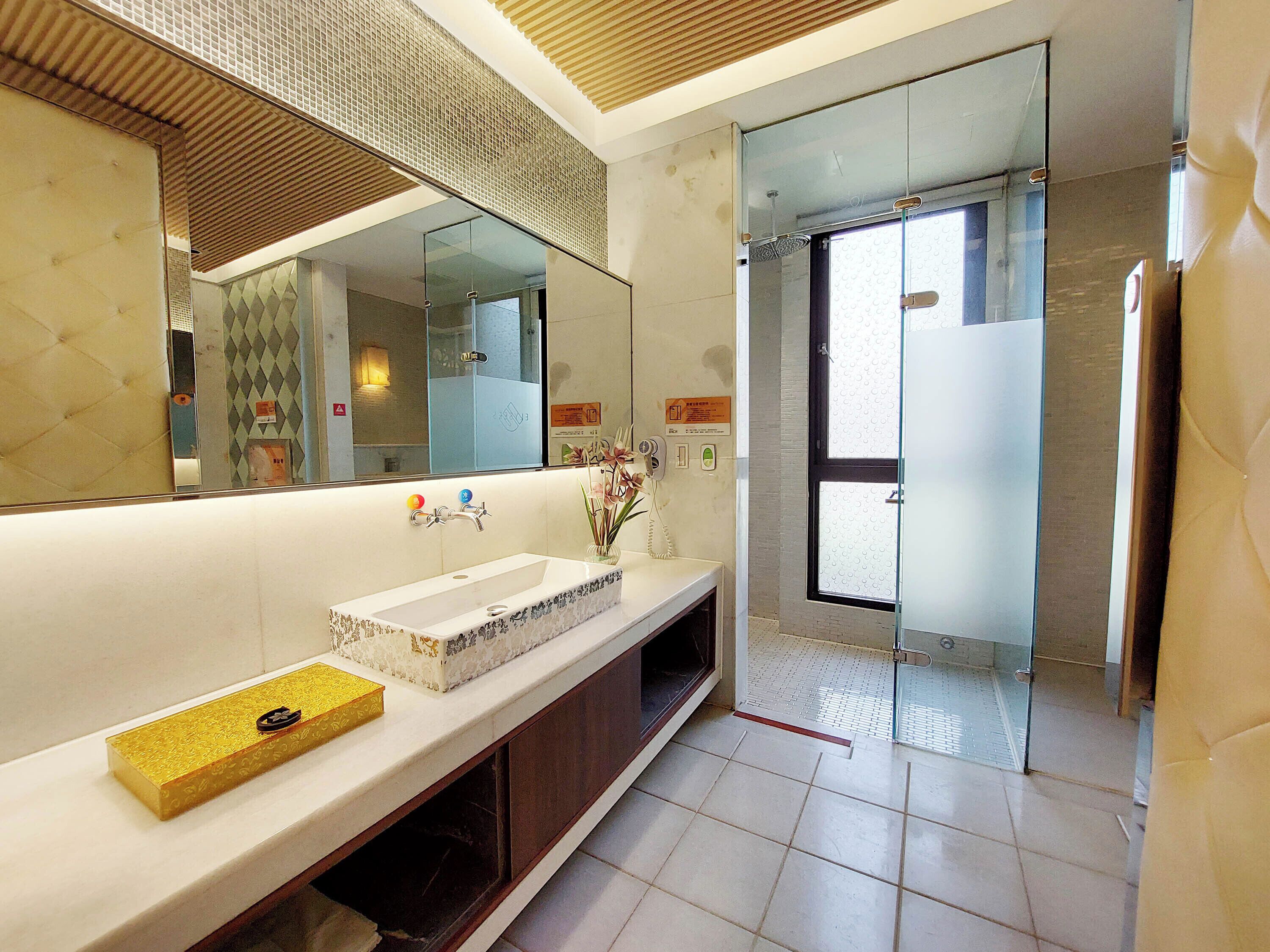 Un baño moderno con un espejo grande, un lavabo blanco, un mueble de tocador y un box de ducha de vidrio.