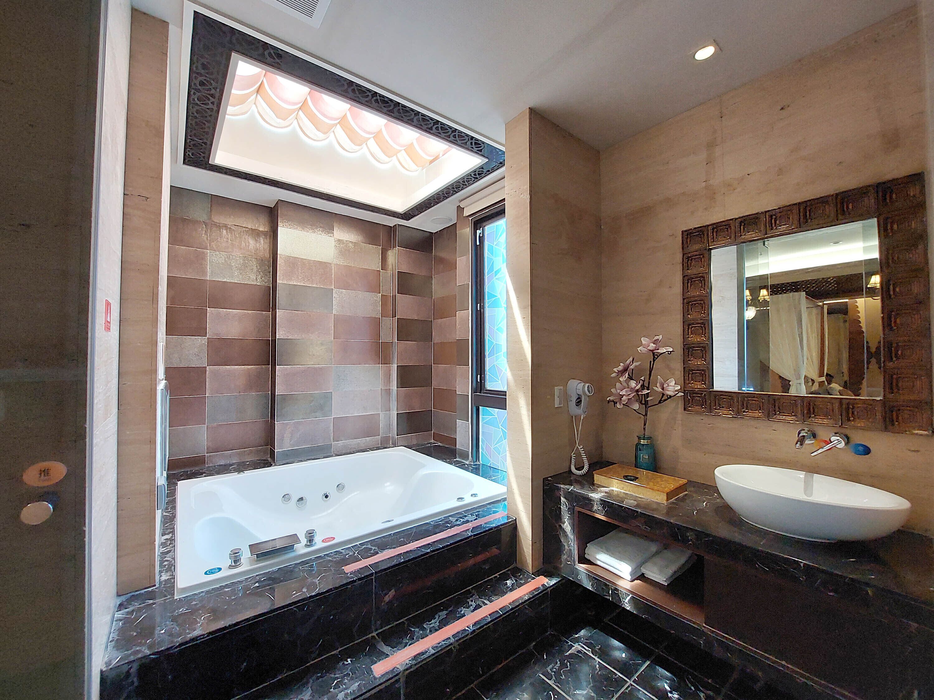 Un baño moderno con una bañera grande, un lavamanos y un espejo.