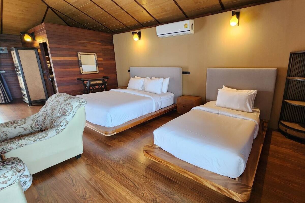 A room with two beds, a chair, and a wooden floor.