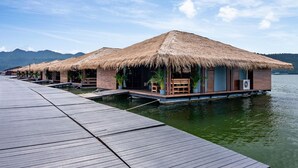 Overwater bungalows with thatched roofs, wooden walkways, and water views. - Ruknam Resort (Si Sawat)