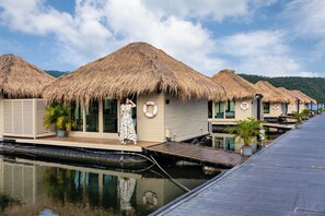 Overwater bungalows with thatched roofs, a pool, and a lifebuoy on the side.