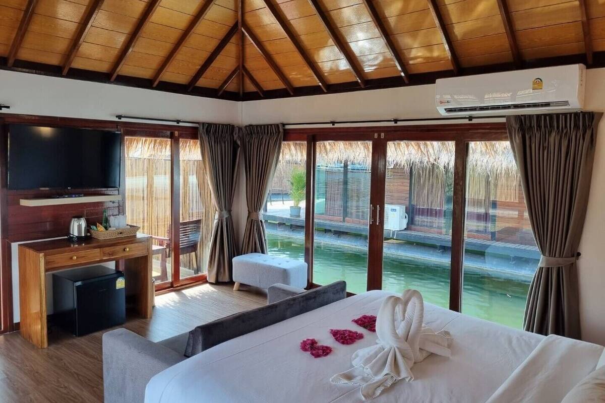 A room with a bed, a TV, a desk, and a window with a view of water.