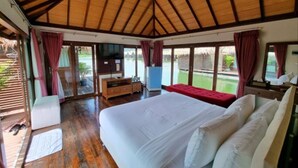 A spacious room with a large bed, a TV, and a view of a pool. - Ruknam Resort (Si Sawat)