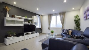 A modern living room with a sofa, a coffee table, a TV, and a cabinet. - Lovely holiday home in Gros Chêne with bubble bath (Gros Chêne)