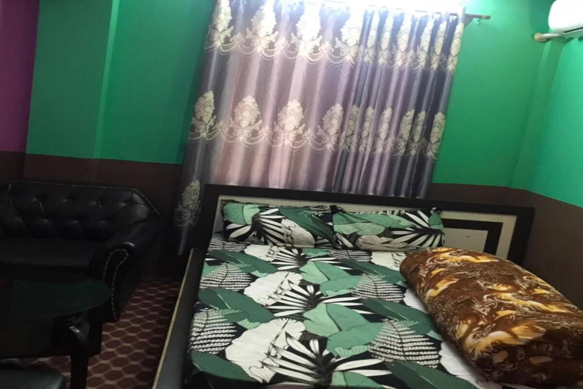 Ein Zimmer mit einem Bett, einem Sessel und einem fenster mit Vorhängen.