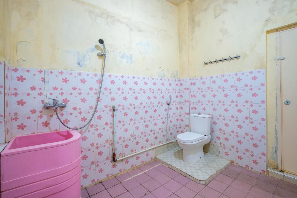 A bathroom with a pink sink, a toilet, and a shower.